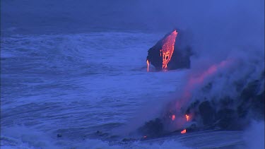 Volcano. At the base of the volcano the lava is flowing directly into the sea. The waves crash onto the volcano and turn immediately to steam.