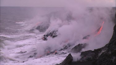 Lava flowing directly into ocean. Waves turning to steam.
