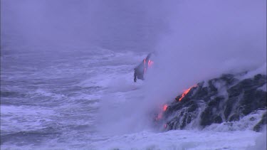 Lava flowing directly into ocean. Waves turning to steam.