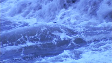 waves crashing directly over incandescent lava at the edge of lava delta volcano