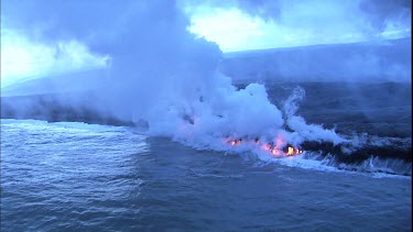 Where the edge of the Kilauea lava delta meets the ocean a line of steam rises into the air