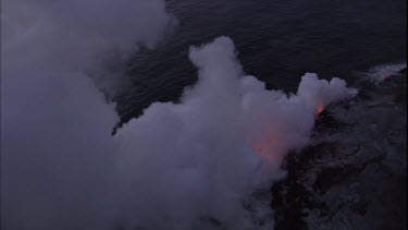 Where the edge of the Kilauea lava delta meets the ocean a line of steam rises into the air. Lava being washed out to sea.