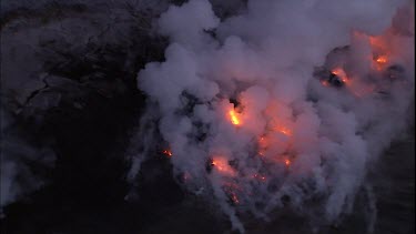 Where the edge of the Kilauea lava delta meets the ocean a line of steam rises into the air. Lava being washed out to sea.