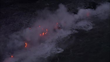 Where the edge of the Kilauea lava delta meets the ocean a line of steam rises into the air.