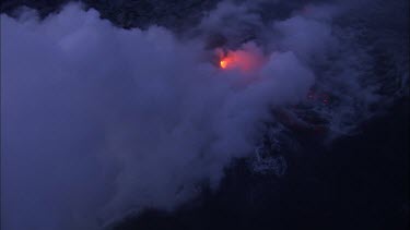 Where the edge of the Kilauea lava delta meets the ocean a line of steam rises into the air.