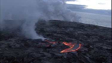 Steam and lava flow. Solidified lava crust. Ocean beyond. This area is called the lava delta.