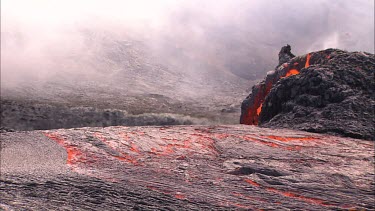 Lava bubbling and erupting from vent and flowing down lava channel