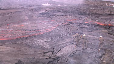 Scientists  throwing meters and measuring equipment into lava flow