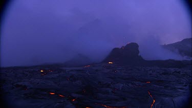 Lava sputtering and erupting out of a vent. Volcanic eruption. Night