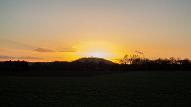 A time-lapse of a sunset over a hill next to a near-city road