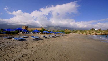 Tourists Walk On Beach, Near Castle & Mountains, Frangokastello, Crete, Greece