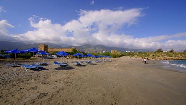 Tourists Walk On Beach, Near Castle & Mountains, Frangokastello, Crete, Greece