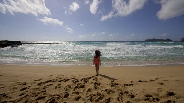 Teenage Girl Walks In & Out Of Sea In Pink Bikini, Falasarna, Crete, Greece