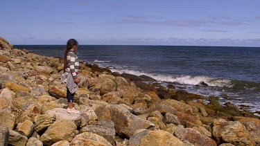 Young Girl Throws Stones Into Sea, North Sea, Scarborough, North Yorkshire, England, United Kingdom