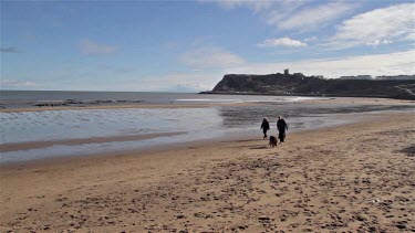 People Walking Alsatian Dog On North Bay Beach, Scarborough, North Yorkshire, England