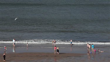 People Playing In Sea & On Beach, Whitby, North Yorkshire, England