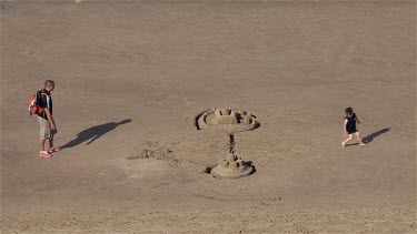 Man Looks At Sand Castles On Beach, Whitby, North Yorkshire, England