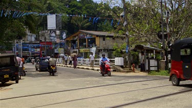Tuc Tucs & People With Umbrellas Cross Tracks, Peradeniya, Sri Lanka