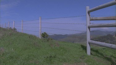 green countryside rolling hills with post and rail fence in foreground