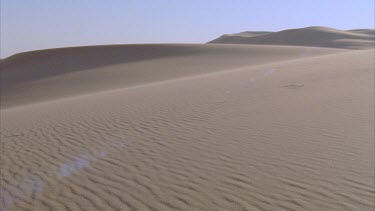 wind blowing sand down sand dune ripples of sand in foreground