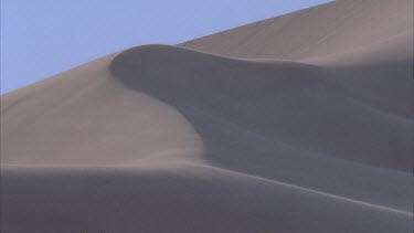 wind blowing sand over tops of dunes
