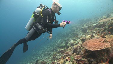 Diver floating in the current over a reef past a fish trap