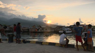 Fishing off a village pier at sunset