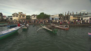Villagers on boats in a harbour
