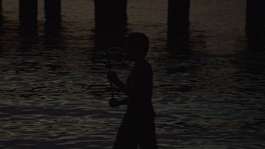 Villager fishing under a pier at sunset