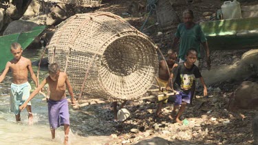 Villagers carrying a large fish trap on the shore