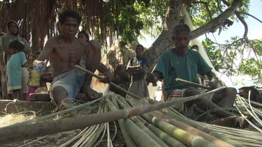 Villagers splitting bamboo on the beach