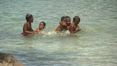 Village children playing in harbour water