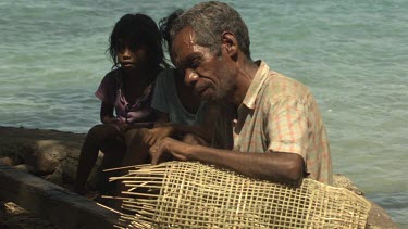 Old man weaving on shore