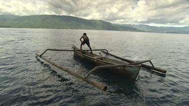Locals pulling a large fish trap onto a canoe