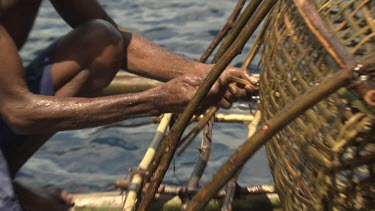 Local with a large fish trap on a canoe