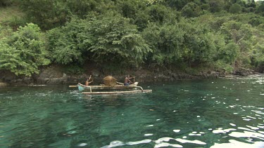 Locals paddling a canoe with a large fish trap by the coast