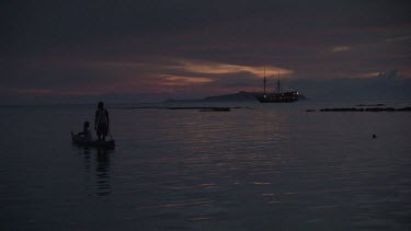 Villagers canoeing at sunset with the Seven Seas ship in the background