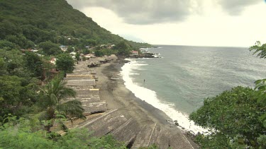 Boat sheds and villagers on a tropical beach