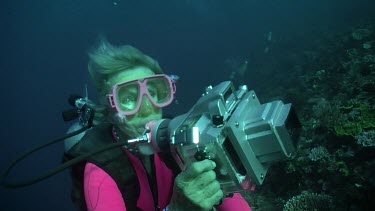 Scuba diver taking photos on the edge of a reef