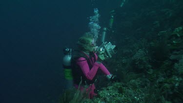 Scuba diver taking photos on the edge of a coral reef
