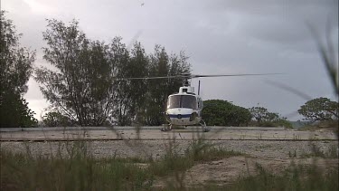 White helicopter taking off from the beach