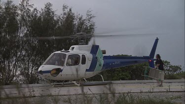 Passengers loading into a white helicopter on the beach