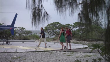 Passengers loading into a white helicopter on the beach