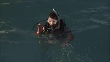 Scuba diver signalling while treading water at the ocean surface
