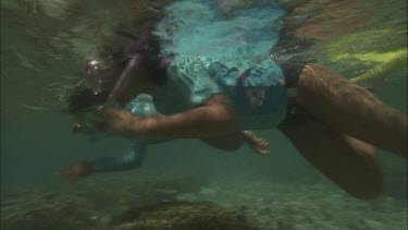 Two girls snorkeling and inspect the coral reef.