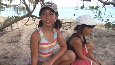 Two girls sit next to a green turtle. Green turtle digs a pit for laying its eggs. One girl says: This is a green turtle. I've never seen one like this before." The other girls adds: "and its laying e...