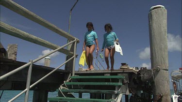 Two girls putting masks and paddles and going for a dive.