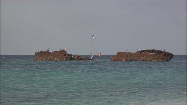 Ruins of a ship, boat sitting on the shore of the sea.