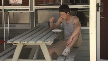 Student researcher resting and eating on benches near canteen