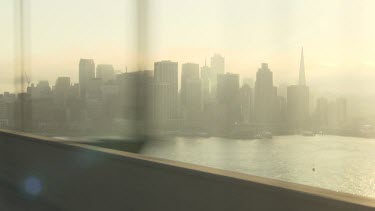 Driving on a bridge into a hazy city at sunrise
